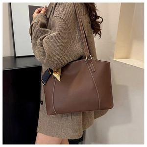 Brown leather tote bag with white contrast stitching and a patterned silk scarf handle detail