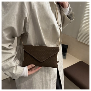Detailed view of the dark brown envelope bag featuring V-shaped texture and gold chain