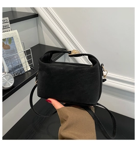 Détail du sac à main en daim noir avec boucle en métal doré et bandoulière supérieure