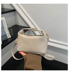 Détail du sac beige montrant la texture du cuir souple et la boucle en métal doré brillant