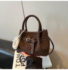 Detail of dark brown tote bag with white contrast stitching and silver buckle accent