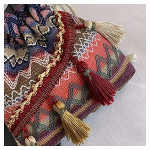 Detail einer Boho-Beuteltasche mit bunten Ethno-Wellenmustern und Quasten-Dekor
