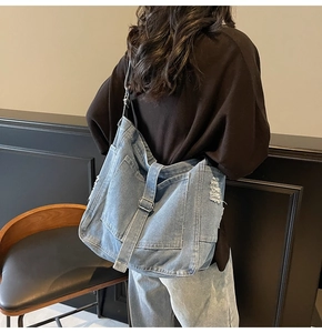 Detailed side view of washed vintage denim tote bag showing distressed frayed edge and strap