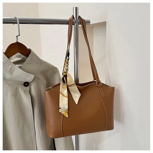 Detail view of caramel brown tote bag featuring contrast stitching and patterned silk scarf