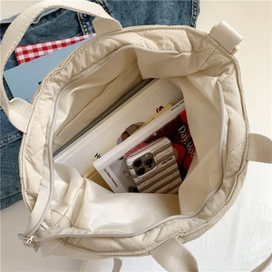Quilted beige puffer tote bag featuring spacious inner compartment and secure zipper pocket