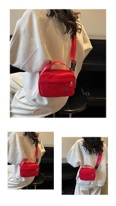 Detail view of red nylon crossbody bag with adjustable strap worn on a gray hoodie