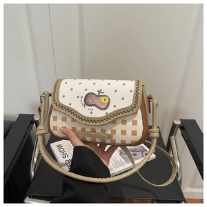 Detail of checkered shoulder bag featuring bow decoration and apple embroidery patch