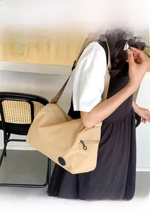 Detail view of khaki nylon bucket bag with wide strap and branded logo in a daily setting