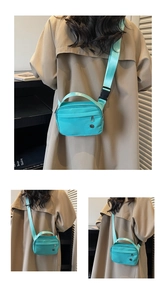 Detail view of mint green nylon crossbody bag with wide strap and zipper pocket