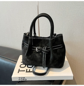 Detail of black suede handbag with white stitching and silver buckle accent