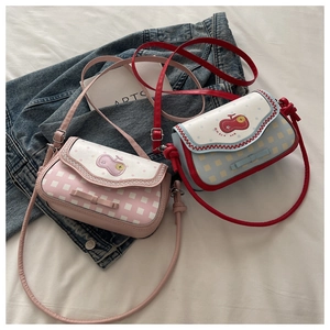 Detail view of plaid crossbody bags with cherry embroidery and wavy edges in pink and blue