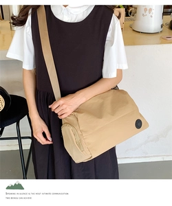 Detail of khaki nylon bucket crossbody bag featuring a side logo and wide shoulder strap