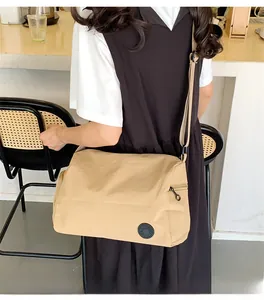 Close-up of beige nylon bucket bag with wide strap and side zipper in a cafe setting