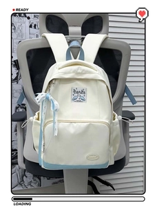 Detail view of cream and blue backpack with lace bow pendant on office chair