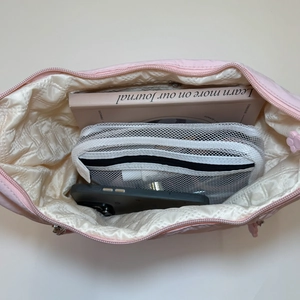 Pink quilted macaron crossbody bag showing spacious interior with notebook and smartphone