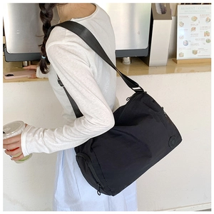 Close-up of the black nylon bucket bag with adjustable wide strap on a female model