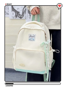 Detailed shot of school backpack with lace bow charm and angel patch decoration