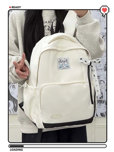 Close-up of cream nylon backpack featuring trendy patches and black and white polka dot ribbon