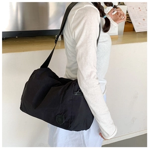 Detail of black nylon crossbody bag showing side zipper pocket and adjustable strap