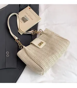 Detail of woven straw tote bag featuring white leather flap and gold metal twist lock