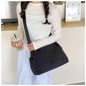 Close-up of black nylon crossbody bag with wide shoulder strap and side zipper pocket