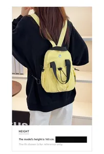 Bright yellow nylon mini backpack with adjustable straps shown on a 165cm female model