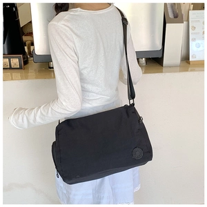 Detailed view of black nylon messenger bag worn cross-body for daily commuting