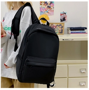 Detail view of the black minimalist canvas backpack featuring durable D-ring and zipper pocket