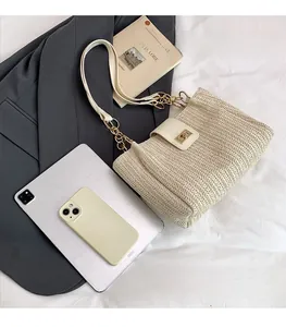 Detail view of woven cream tote bag showing gold metal twist lock and chain strap texture