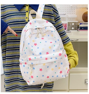 Close-up of white canvas backpack featuring vibrant colorful star patterns and front pocket
