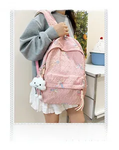 Close-up of pink striped backpack featuring floral embroidery and cloud plush charm