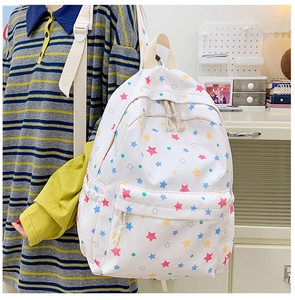 Detail view of a white student backpack with colorful star patterns in a home setting
