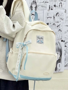 Detail of white canvas backpack with light blue ribbon bow and Tanke brand label