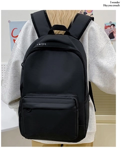 Detailed back view of a minimalist black canvas backpack with wide padded straps
