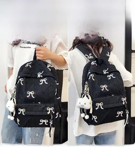 Detail of black quilted backpack featuring colorful bow embroidery and white cloud charm