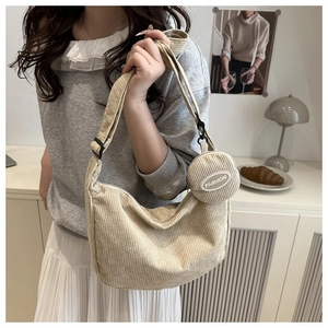 Detail of off-white corduroy hobo bag featuring a detachable mini round coin purse with fashion text