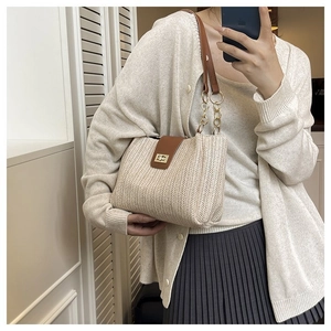 Detail of beige woven straw tote bag with brown leather flap and gold chain strap