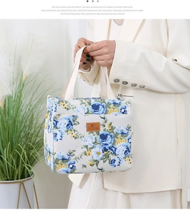 Detail of floral canvas tote bag showing brown leather label and cream webbing handle