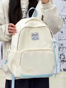 Detail view of white canvas backpack with blue accents and wing embroidery decoration
