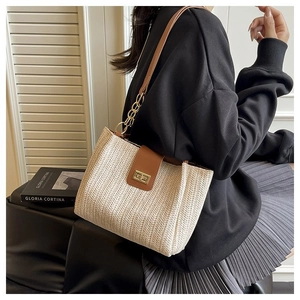 Close-up of beige woven tote with herringbone pattern and gold-tone metal twist lock