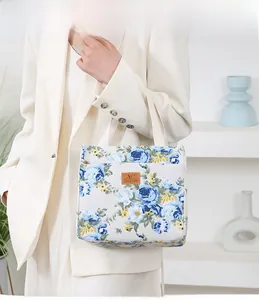 Close-up of floral canvas tote bag with leather logo patch and sturdy top handles