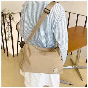 Detail of khaki nylon bucket bag showing wide shoulder strap and side zipper pocket