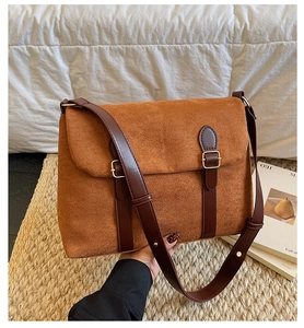 Close-up of caramel suede shoulder bag featuring retro leather straps and gold metal buckles
