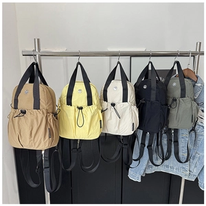 Multi-color nylon backpacks in earth tones, yellow, white, black, and green displayed on a rack