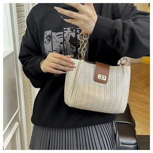 Detail of hand-woven tote bag with brown leather flap and gold circular chain handle