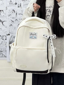 Detail of white canvas backpack with polka dot lace bow and embroidered wing patch design