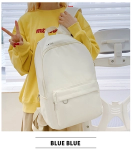 Close-up of beige canvas backpack featuring a metal ring zipper and top geometric icon