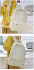 Detail view of the cream minimalist canvas backpack featuring a front zipper pocket and D-ring