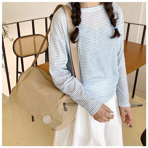 Detail of khaki nylon bucket bag with wide strap worn by a model in casual lifestyle setting