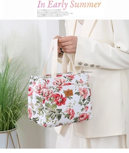 Detail shot of canvas lunch bag with red floral print and leather brand label